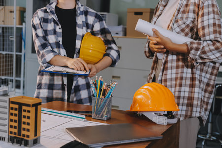 Construction and structure concept of engineer working drawing on blueprint meeting for project working with partner on model building and engineering tools in working site, construction concept.の写真素材