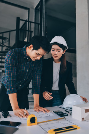 Construction manager and engineer dressed in hard helmets explore construction documentation on the building site near the steel framesの写真素材