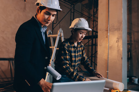 Construction manager and engineer dressed in hard helmets explore construction documentation on the...