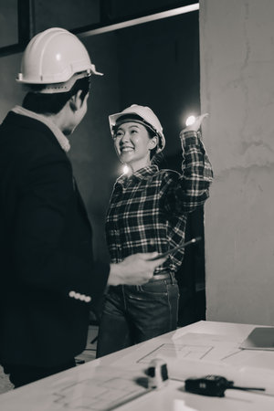 Construction manager and engineer dressed in hard helmets explore construction documentation on the building site near the steel framesの写真素材