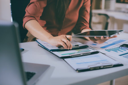 Portrait of young Hispanic professional business woman standing in office. Happy female company executive, smiling businesswoman entrepreneur corporate leader manager looking at camera using tabletの写真素材
