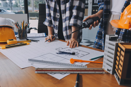 Construction and structure concept of engineer working drawing on blueprint meeting for project working with partner on model building and engineering tools in working site, construction concept.の写真素材