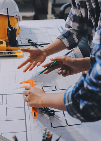 Construction and structure concept of engineer working drawing on blueprint meeting for project working with partner on model building and engineering tools in working site, construction concept.の写真素材