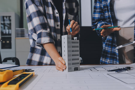 Construction and structure concept of engineer working drawing on blueprint meeting for project working with partner on model building and engineering tools in working site, construction concept.の写真素材