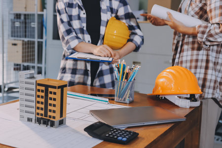 Construction and structure concept of engineer working drawing on blueprint meeting for project working with partner on model building and engineering tools in working site, construction concept.の写真素材