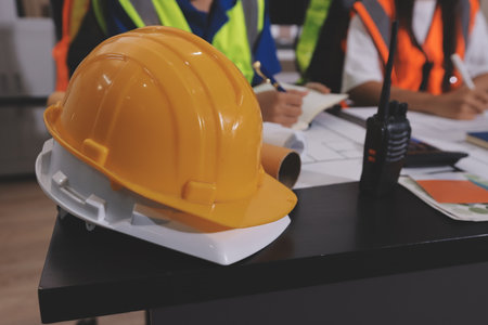 Closeup of team of industrial engineers meeting analyze machinery blueprints consult project on...