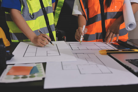 Closeup of team of industrial engineers meeting analyze machinery blueprints consult project on...