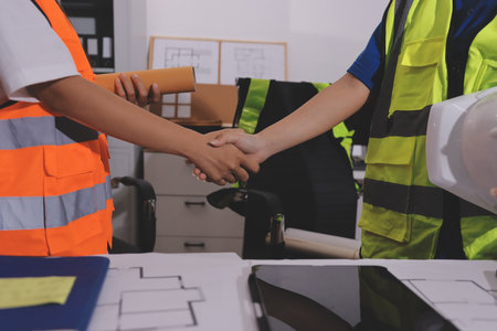 Closeup of team of industrial engineers meeting analyze machinery blueprints consult project on table in manufacturing factory. Working in manufacturing plant or production plant.の写真素材