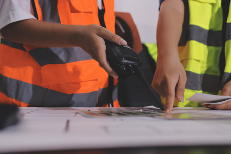 Closeup of team of industrial engineers meeting analyze machinery blueprints consult project on table in manufacturing factory. Working in manufacturing plant or production plant.の写真素材