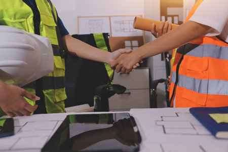 Closeup of team of industrial engineers meeting analyze machinery blueprints consult project on table in manufacturing factory. Working in manufacturing plant or production plant.の写真素材