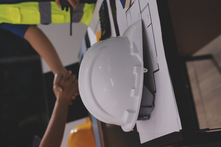 Closeup of team of industrial engineers meeting analyze machinery blueprints consult project on table in manufacturing factory. Working in manufacturing plant or production plant.の写真素材