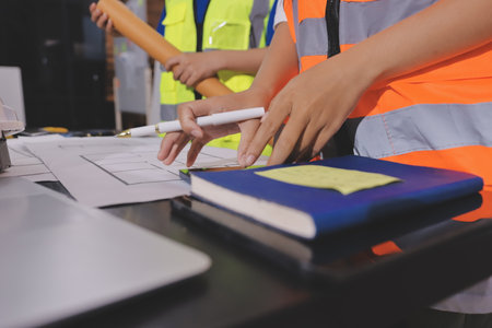 Closeup of team of industrial engineers meeting analyze machinery blueprints consult project on...