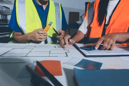 Closeup of team of industrial engineers meeting analyze machinery blueprints consult project on...