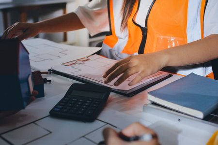 Closeup of team of industrial engineers meeting analyze machinery blueprints consult project on...