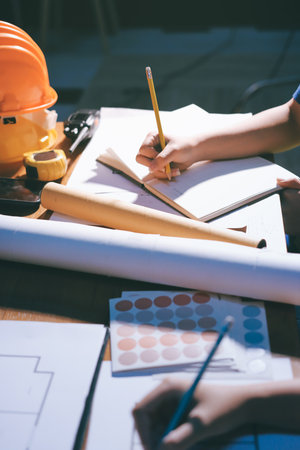 Closeup of team of industrial engineers meeting analyze machinery blueprints consult project on...