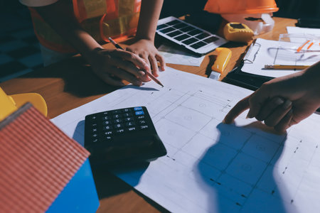 Closeup of team of industrial engineers meeting analyze machinery blueprints consult project on...