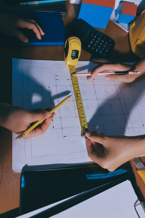 Closeup of team of industrial engineers meeting analyze machinery blueprints consult project on table in manufacturing factory. Working in manufacturing plant or production plant.の写真素材