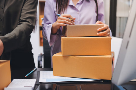 Portrait of Starting small businesses SME owners, two Asian woman check online orders Selling products working with boxes freelance work at home office, sme business online small medium enterpriseの写真素材