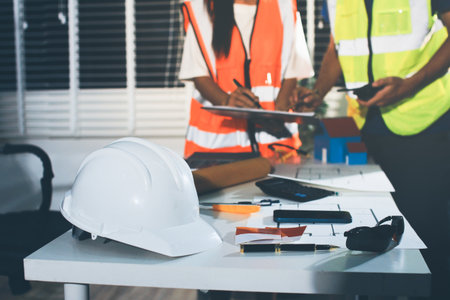 Closeup of team of industrial engineers meeting analyze machinery blueprints consult project on...
