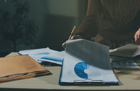 Close-up of businessman's hands making notes, chart, desk, office