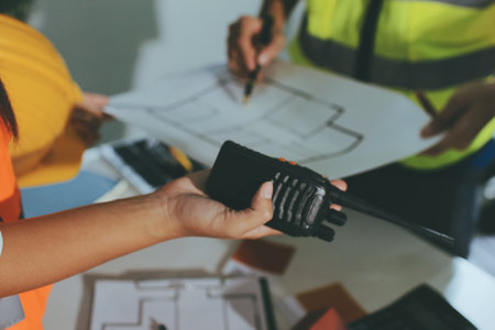 Closeup of team of industrial engineers meeting analyze machinery blueprints consult project on...