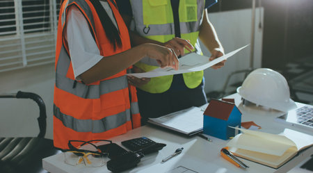 Closeup of team of industrial engineers meeting analyze machinery blueprints consult project on...