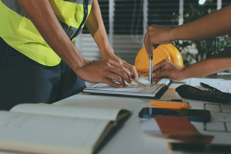 Closeup of team of industrial engineers meeting analyze machinery blueprints consult project on...
