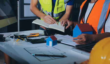 Closeup of team of industrial engineers meeting analyze machinery blueprints consult project on...