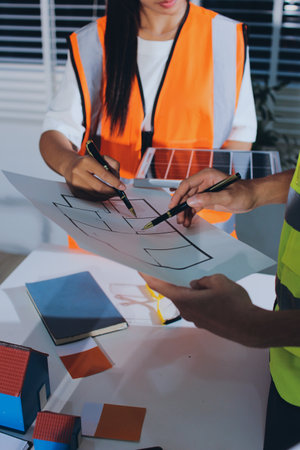 Closeup of team of engineers meeting analyze machinery blueprints consult project on table in...