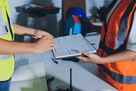 Closeup of team of industrial engineers meeting analyze machinery blueprints consult project on table in manufacturing factory. Working in manufacturing plant or production plant.の写真素材