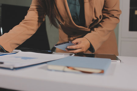 Close-up of businessman's hands making notes, mobiles, chart, desk, office