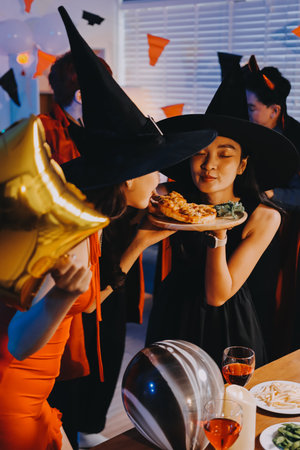 Joyful Halloween party with coworkers in costumes, celebrating with drinks and laughter, fostering teamwork and festive spiritの写真素材