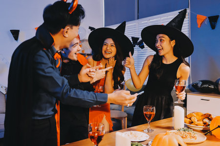 Joyful Halloween party with coworkers in costumes, celebrating with drinks and laughter, fostering teamwork and festive spiritの写真素材
