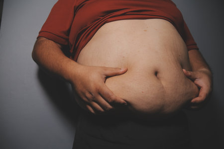 Asian man in front of a mirror looks at his body. Excess belly fat, Unhealthy lifestyle, Diet concept.の写真素材