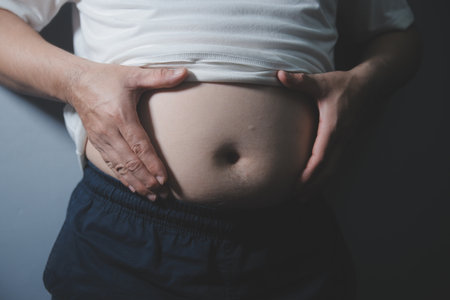 Asian man in front of a mirror looks at his body. Belly, Unhealthy lifestyle, Diet concept.の写真素材