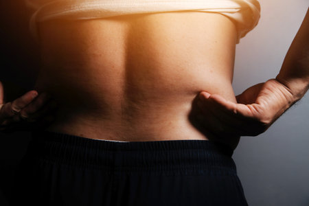 Asian man in front of a mirror looks at his body. Excess belly fat, Unhealthy lifestyle, Diet concept.の写真素材