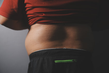 Asian man in front of a mirror looks at his body. Excess belly fat, Unhealthy lifestyle, Diet...