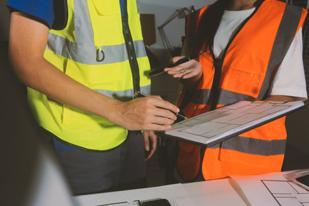 Closeup of team of industrial engineers meeting analyze machinery blueprints consult project on table in manufacturing factory. Working in manufacturing plant or production plant.の写真素材