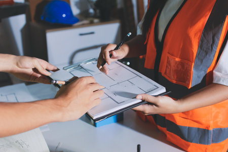 Closeup of team of industrial engineers meeting analyze machinery blueprints consult project on table in manufacturing factory. Working in manufacturing plant or production plant.の写真素材
