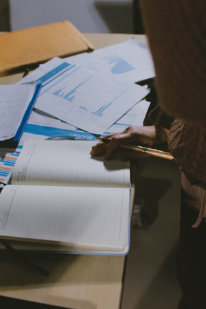 Close-up of businessman's hands making notes, mobiles, chart, desk, office