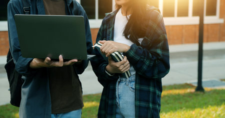Happy students walking together on university campus, chatting and laughing outdoors after classesの写真素材