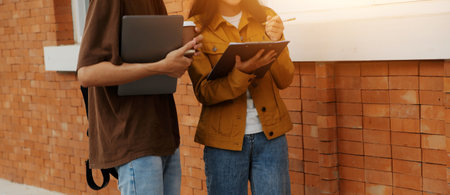 Happy students walking together on university campus, chatting and laughing outdoors after classesの写真素材