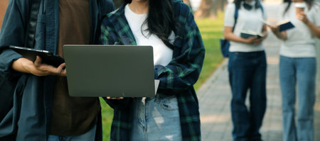 Happy students walking together on university campus, chatting and laughing outdoors after classesの写真素材