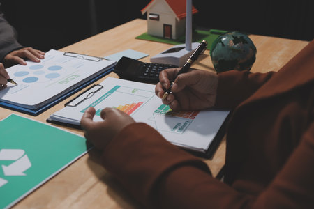 Asian woman lead young group of multiethnic businesspeople in team meeting, using laptop computer for ESG topic presentation on monitor. Sustainable business practice, people work at home conceptの写真素材
