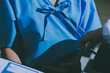 Doctor checking patient's heart with stethoscope at a hospitalの写真素材