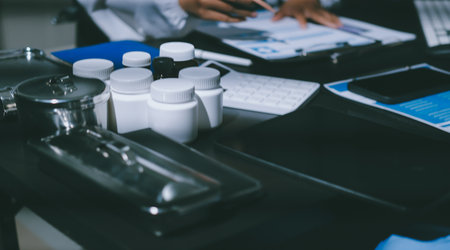 Two doctors and a female nurse meet at a table in the hospital, collaborating on medical tasks using...