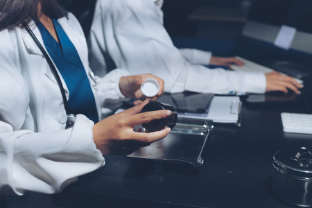 Two doctors and a female nurse meet at a table in the hospital, collaborating on medical tasks using...