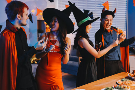 Joyful Halloween party with coworkers in costumes, celebrating with drinks and laughter, fostering teamwork and festive spiritの写真素材
