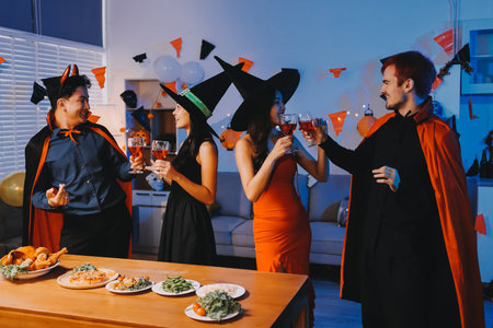 Joyful office Halloween party with coworkers in costumes, celebrating with drinks and laughter, fostering teamwork and festive spiritの写真素材