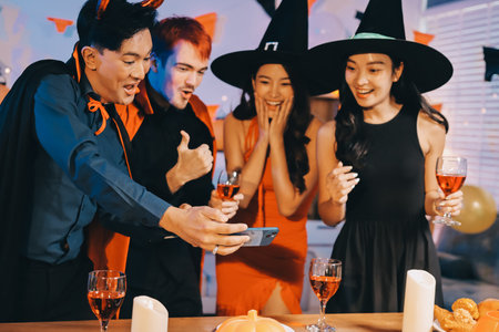 Joyful office Halloween party with coworkers in costumes, celebrating with drinks and laughter, fostering teamwork and festive spiritの写真素材